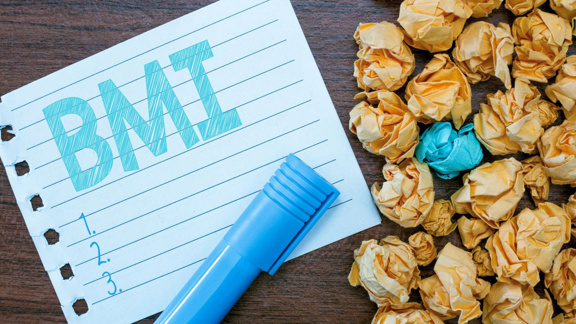 A handwritten note with "BMI" in bold letters, a blue marker, and crumpled yellow paper balls.