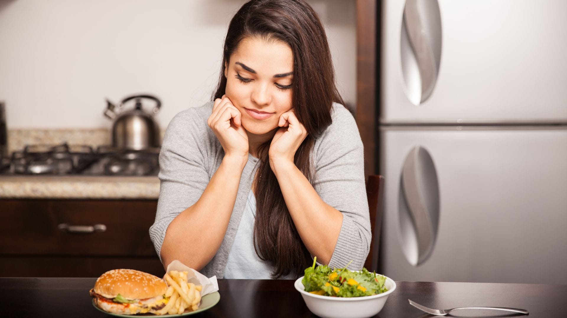 Woman deciding between a burger and a salad.
