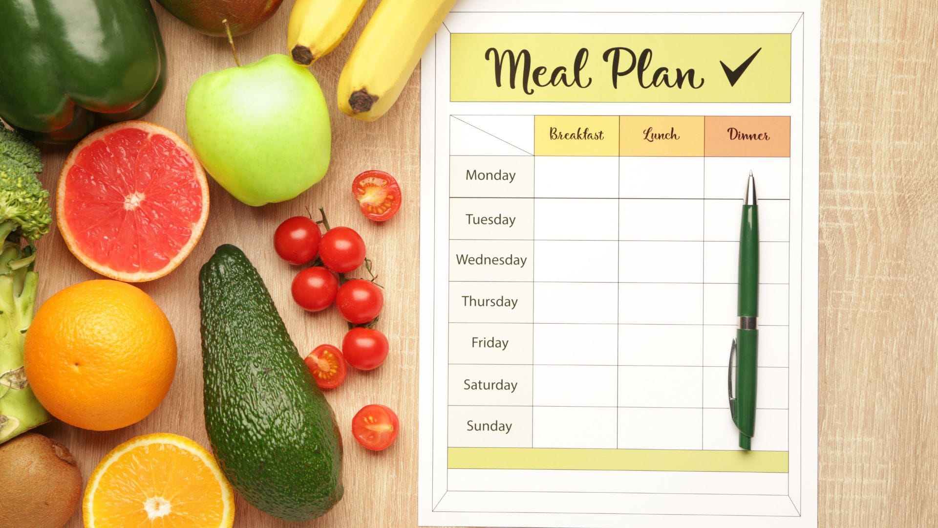 Meal plan template surrounded by fresh fruits and vegetables.