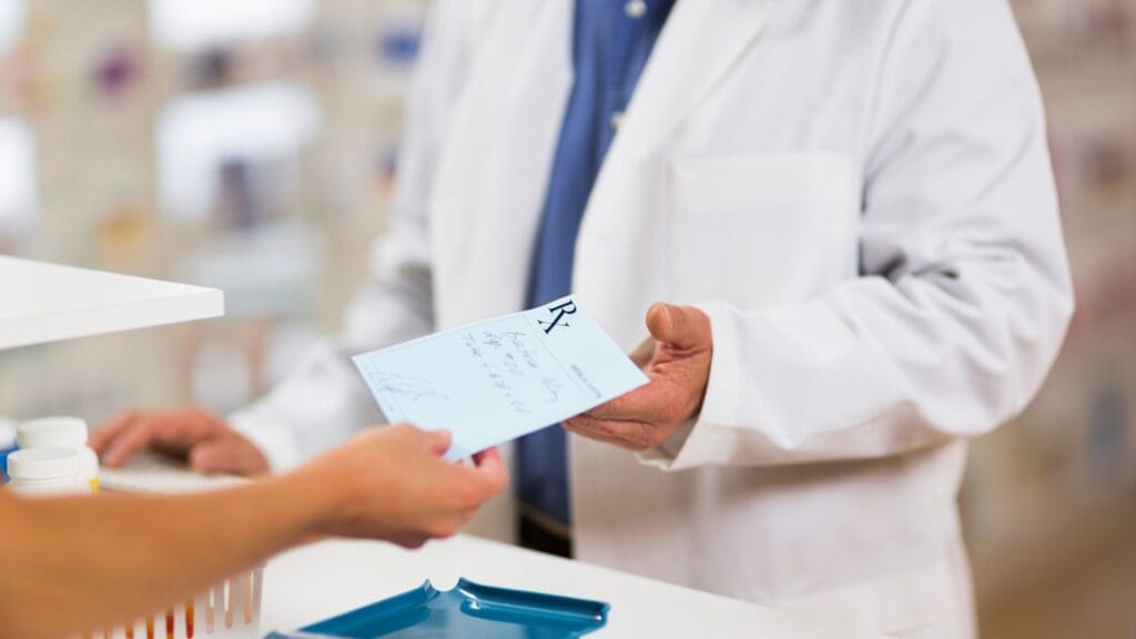 A pharmacist handing a prescription to a customer.