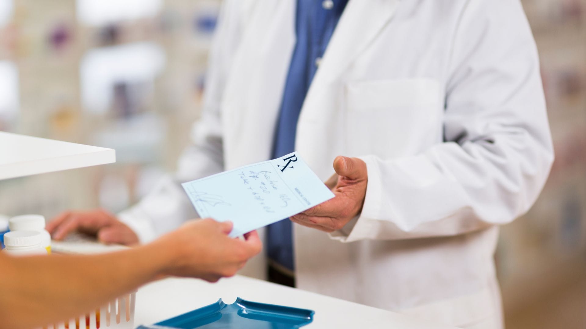 A pharmacist handing a prescription to a customer.