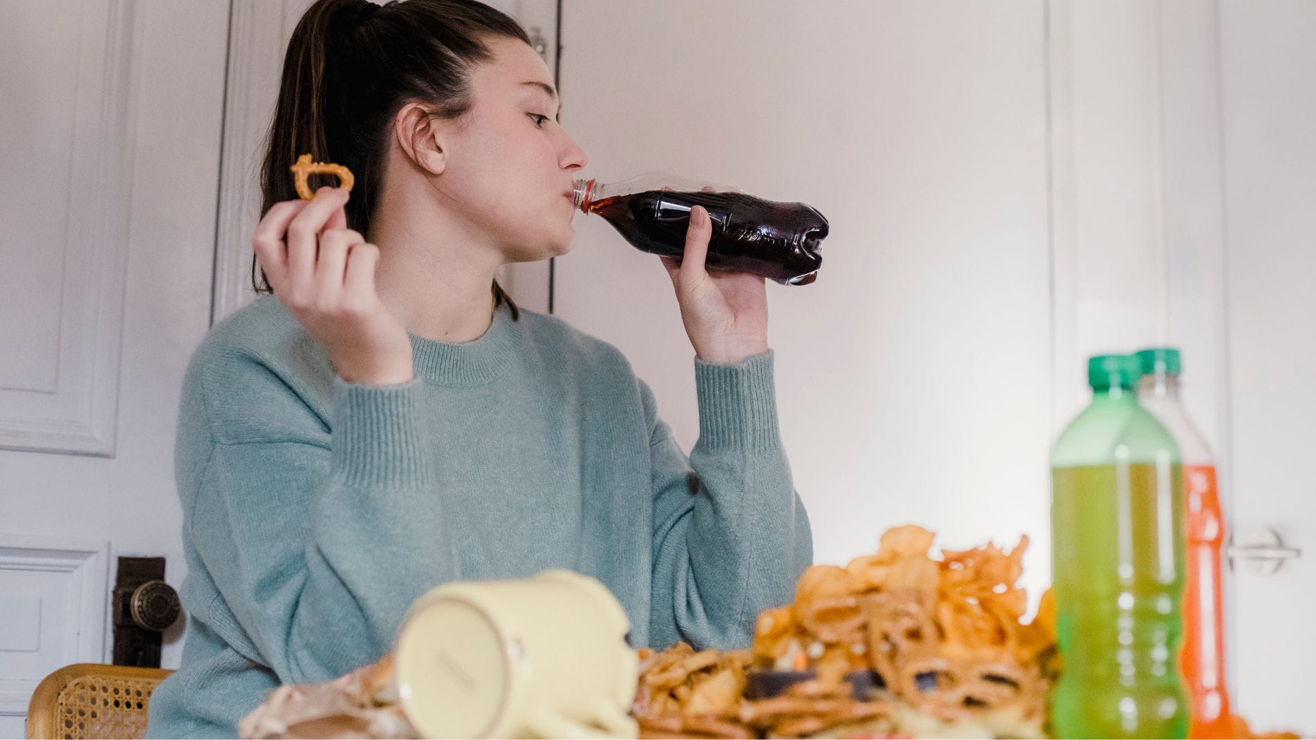 Woman drinking soda and eating chips.