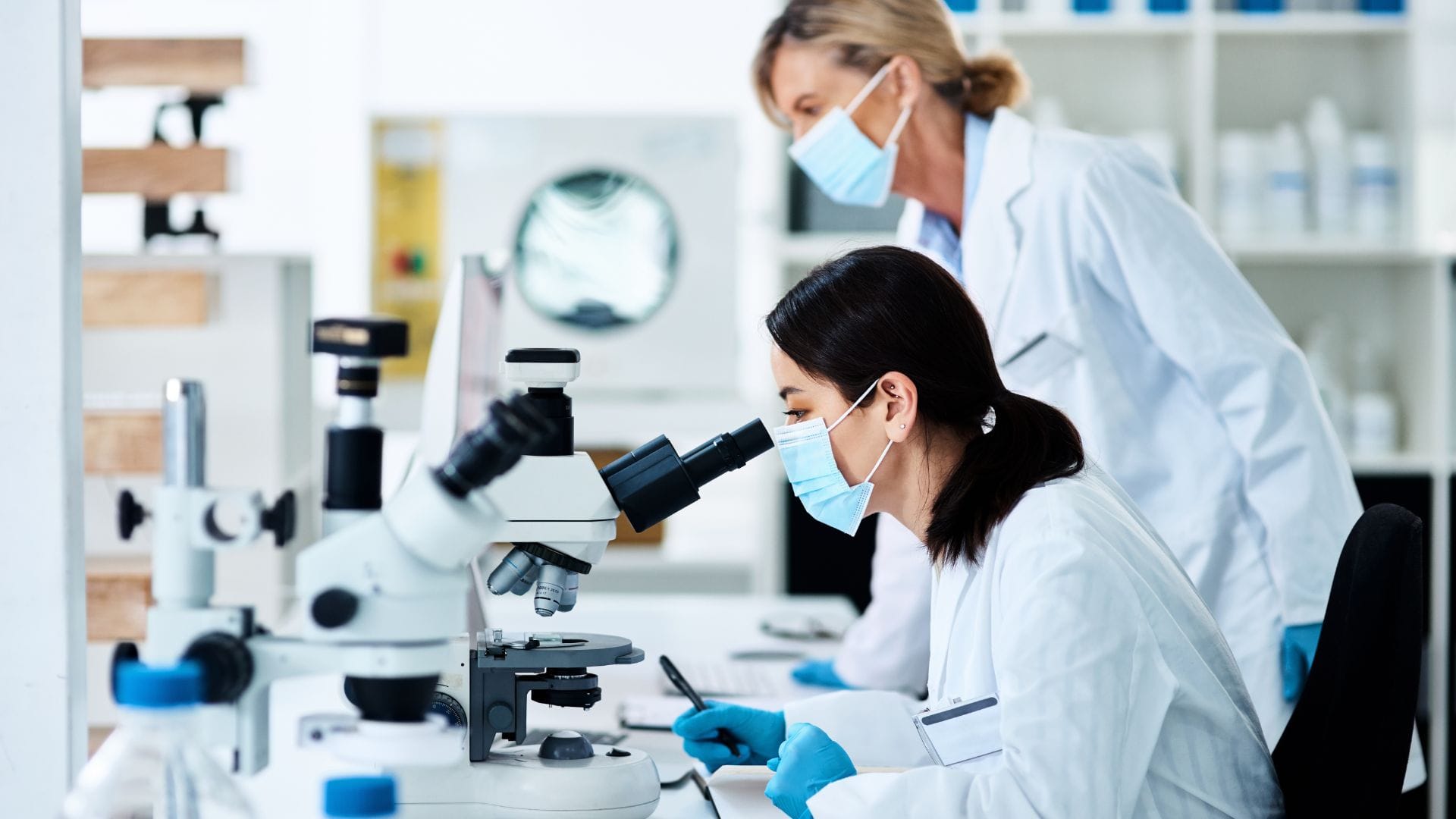 Scientists in a lab analysing samples under a microscope.