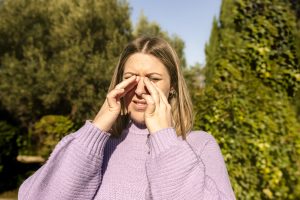 woman scratching eyes in park