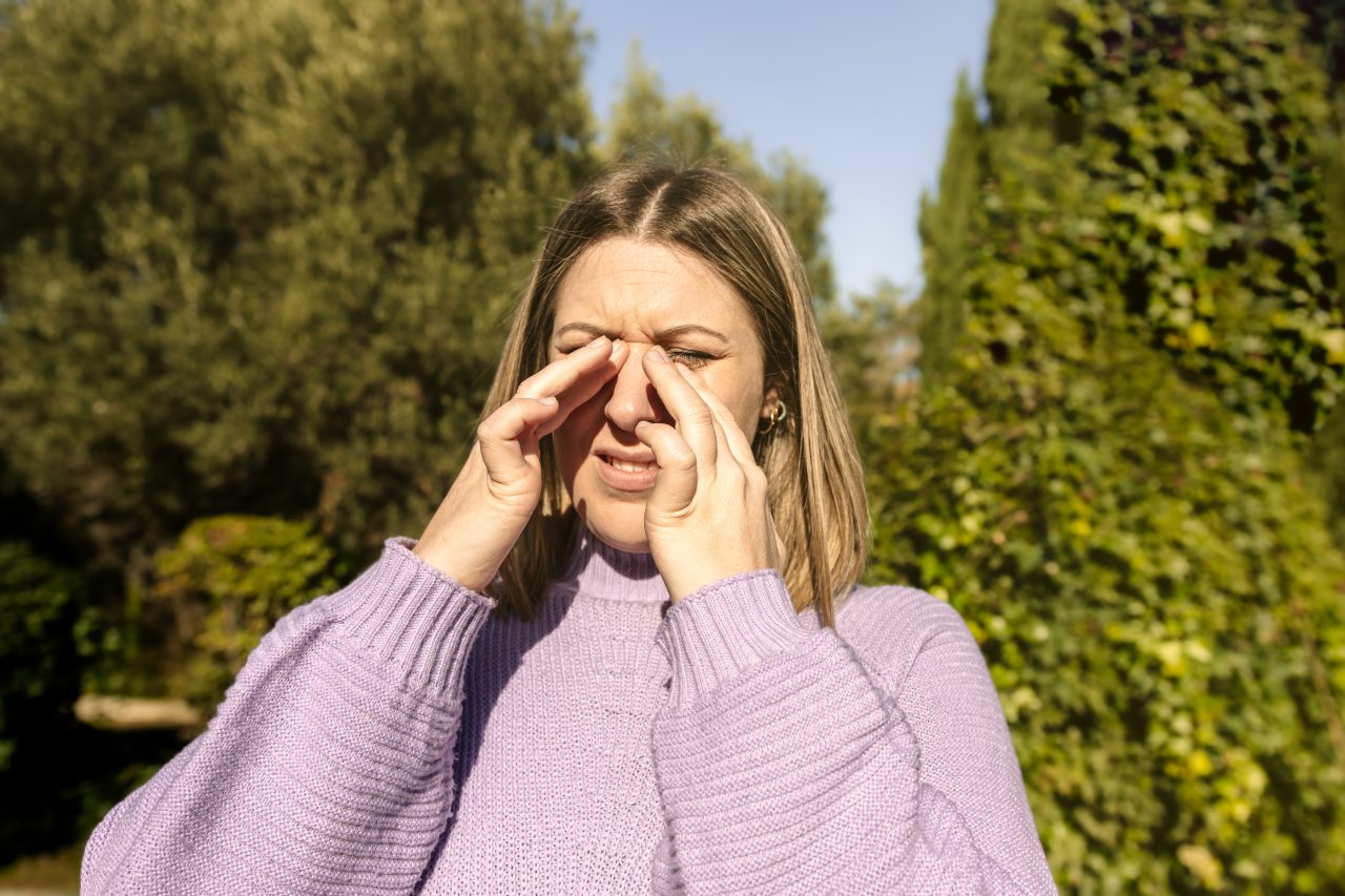 woman scratching eyes in park