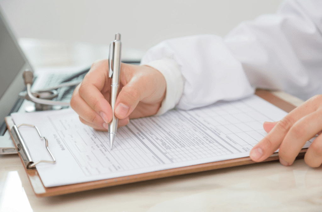 Healthcare professional completing a medical form on a clipboard, representing prescription approval for migraine medication.