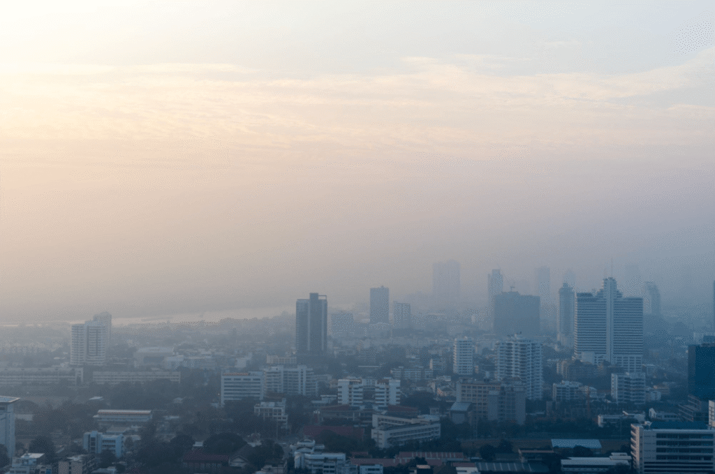 Hazy city skyline covered by air pollution and smog during sunrise, illustrating how poor air quality can worsen hay fever symptoms.