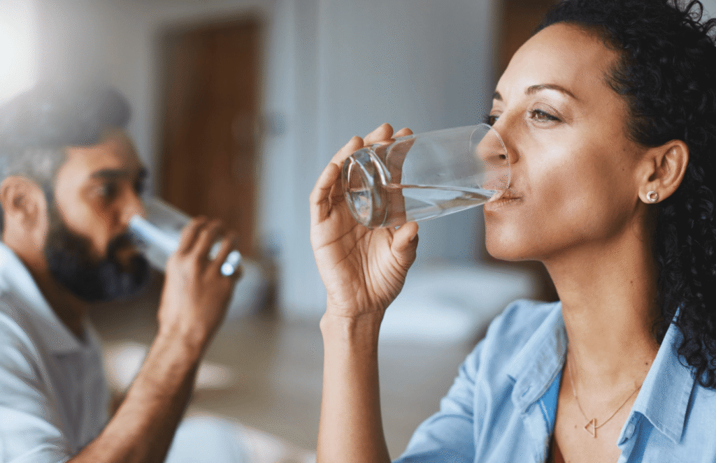 Two adults drinking glasses of water at home to stay hydrated during a migraine and support recovery.
