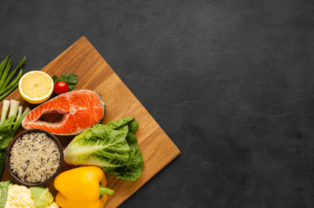 Fresh salmon, brown rice and vegetables arranged on a wooden board, representing a healthy diet that supports hair health.