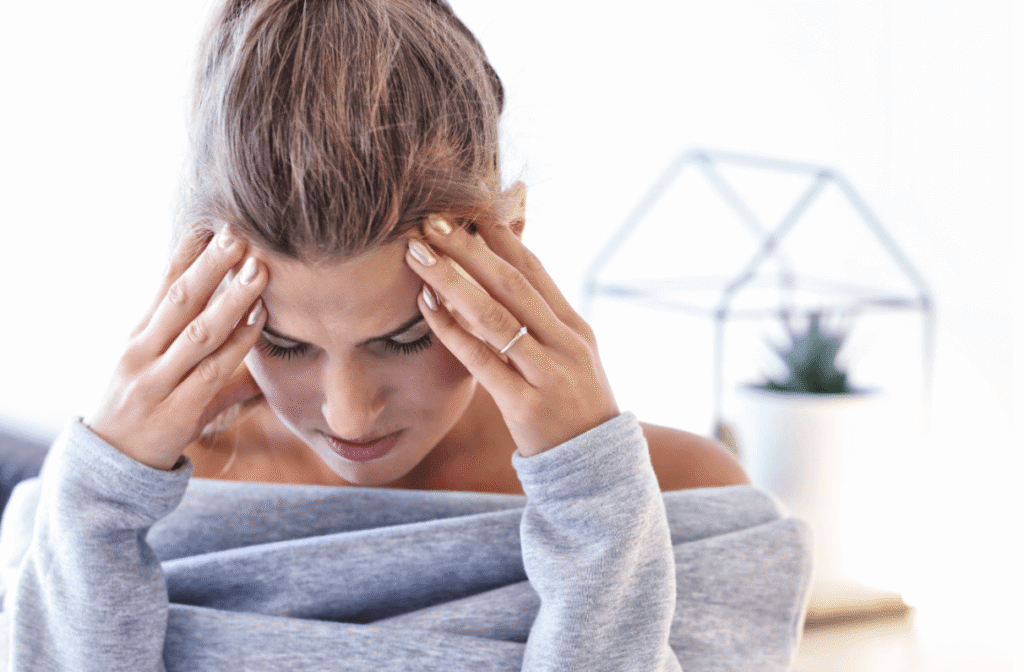 Woman pressing her temples while experiencing a headache or migraine indoors.