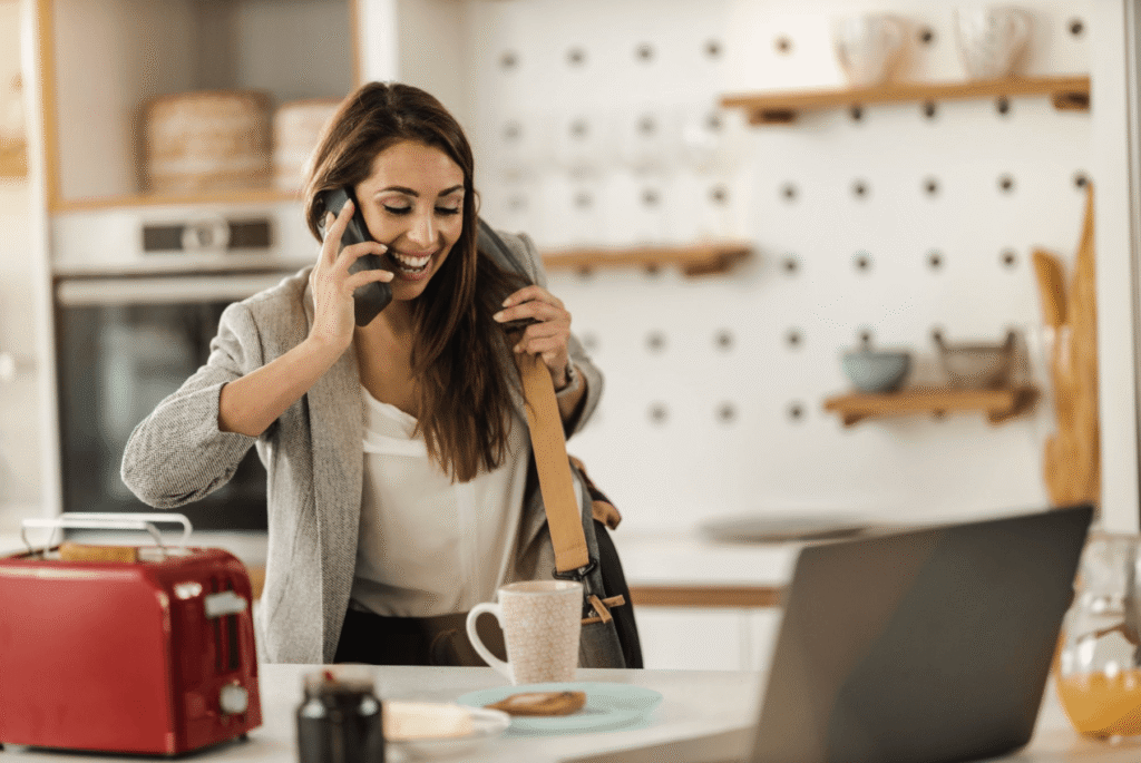 Woman talking on her phone in a home office while getting ready for work, representing managing periods around busy schedules.