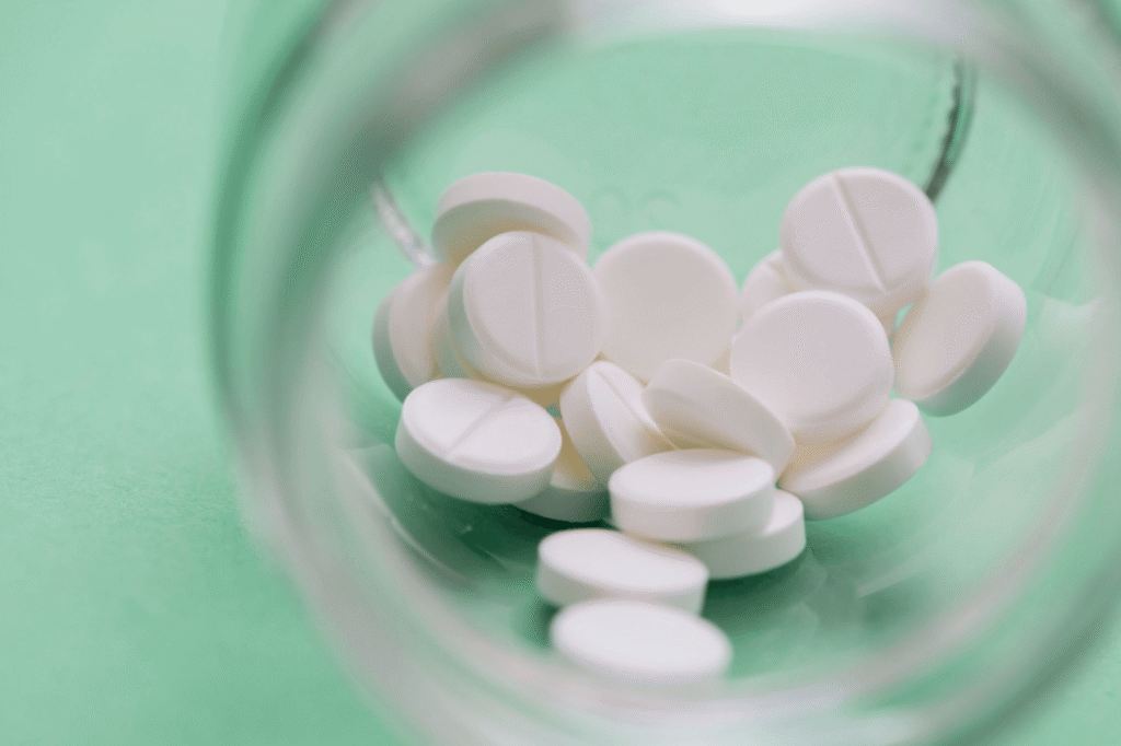 White tablets in an open container, representing medication used to help manage premature ejaculation symptoms.