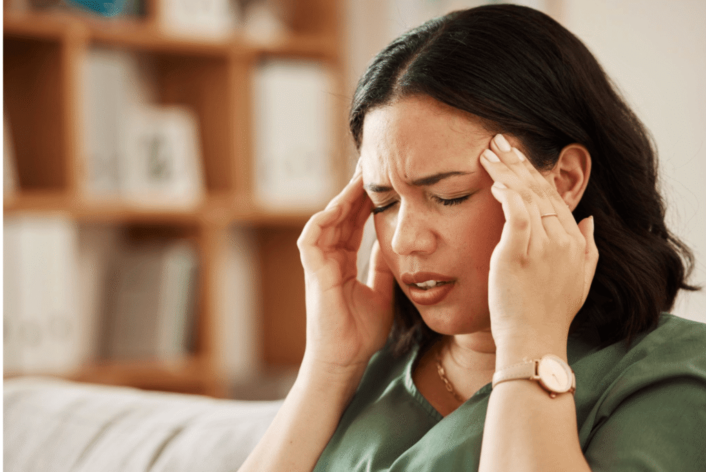 Woman pressing her temples during a migraine attack, representing how migraine treatments are selected based on symptoms.