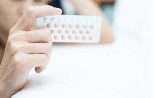 Person holding a blister pack of contraceptive pills in front of the camera.