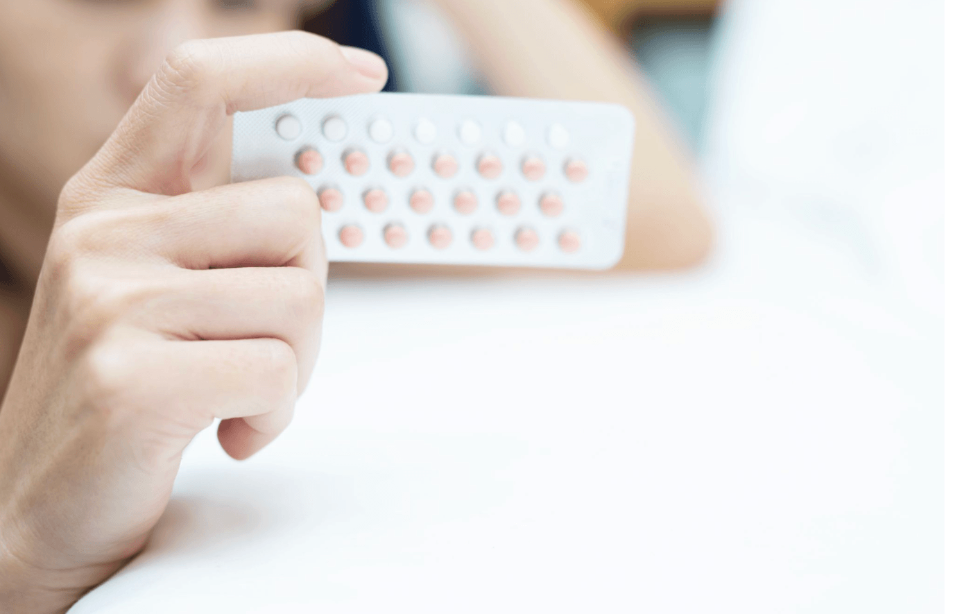 Person holding a blister pack of contraceptive pills in front of the camera.